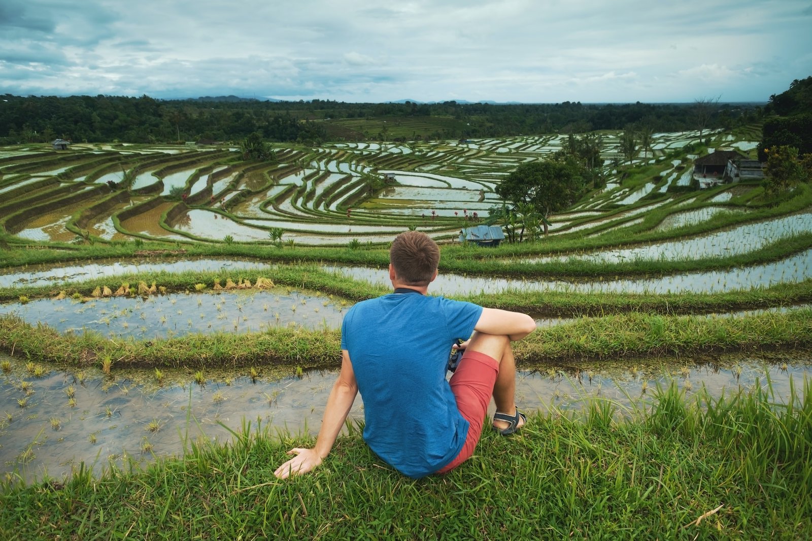 Young Man Traveler sitting and relaxing outdoor at rice fields on terraced in Bali Indonesia